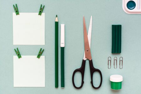 Stationery - sheets for notes clipped, pencil, felt-tip pen, scissors, gouache, plasticine and watercolor on a green background. Top Viewの写真素材