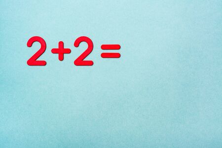 The school task - two plus two - is lined with red plastic figures on a green background. Top View....