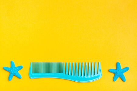 Plastic comb and two hairpins in the form of a starfish on a yellow background. Top viewの写真素材