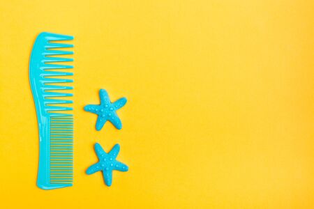 Plastic comb and two hairpins in the form of a starfish on a yellow background. Top view