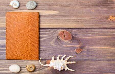 Passport, stone and seashells on a wooden background. Retro style. Place for the inscription. Vacation concept.の写真素材