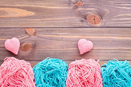 Tangles of pink and mint yarn and knitting hearts on a wooden background. Top viewの写真素材