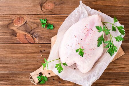 Raw chicken breast on a frame in spices and herbs on a cutting board on a wooden table. Top viewの写真素材
