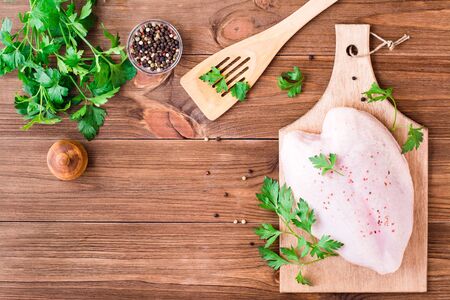 Raw chicken breast on a frame in spices and herbs on a cutting board on a wooden table. Top viewの写真素材