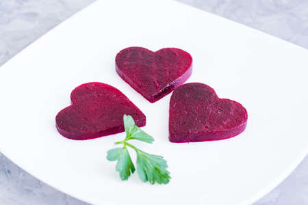 Boiled beet sliced in the form of heart and parsley on a plateの写真素材