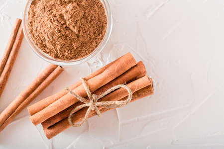 Cinnamon sticks, tied with a rope, and ground cinnamon in a bowl lie on the table. Top view