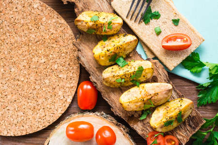 Slices of baked potatoes with spices and herbs on the bark of a tree. Top viewの写真素材