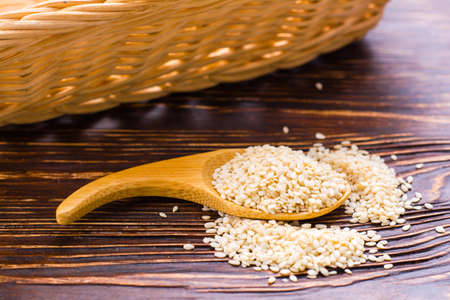 Sesame seeds in a wooden spoon on the tableの写真素材