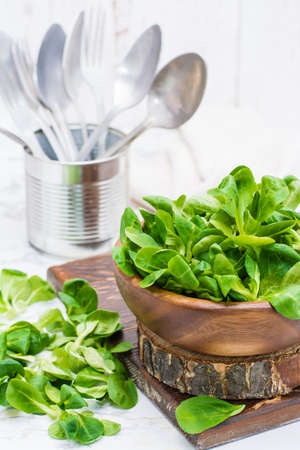 Lettuce leaves in a wooden bowl and on a tableの写真素材