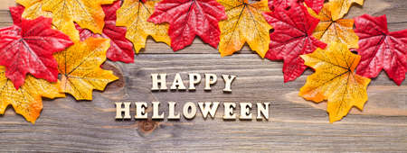 Halloween web banner. The inscription lettering on a wooden background surrounded by maple leavesの写真素材