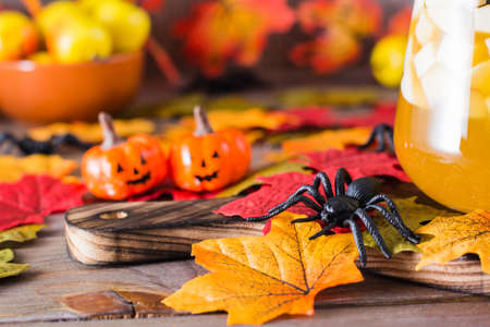 Halloween decorations. Spider, pumpkins and fallen autumn leaves on a wooden tableの写真素材