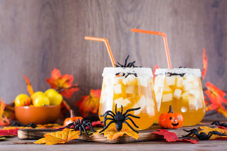 Halloween cocktails. Fruit juice with apple and ice pieces in glasses on a wooden tableの写真素材
