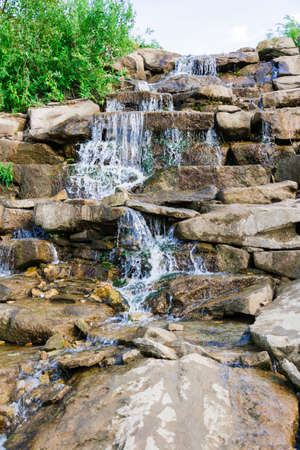 River waterfall. Small jets of water flow down the stones on a sunny dayの写真素材