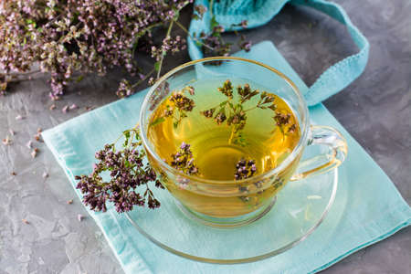 Herbal treatment. Tea with oregano in a cup on the table close-up. Relaxing drink