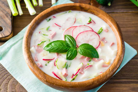 Russian kitchen. Okroshka - cold soup with vegetables, sausages and herbs on kefir. Rustic style. Close-upの写真素材