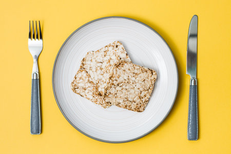 Healthy eating. Crispbread made from oats, wheat, flax and sesame seeds on a plate and cutlery on a...