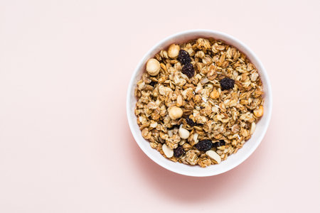 Healthy eating. Baked oats, nuts and raisins granola in a bowl on a pink background. Top viewの写真素材