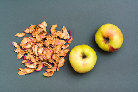 Handful of pieces of dry apples and fresh apples on a green background. Top viewの写真素材