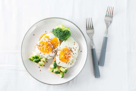 Bruschetta with scrambled eggs and broccoli on a grain crispbread with sesame seeds and flaxseed on...