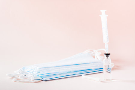 Vaccination and Immunization. Syringe needle inserted into glass vaccine vial and face maskの写真素材