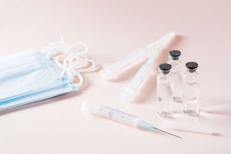 Vaccination and Immunization. Opened syringe in front of glass vials with vaccine, protective masks...