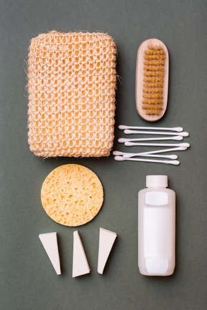 Body care. Bathroom set - washcloth, shampoo, sponges, cotton swabs and a brush on a green background. Vertical viewの写真素材