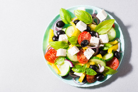 Fresh homemade greek salad with basil leaves on a plate on the table. Domestic life. Top view. Copy space. Top viewの写真素材