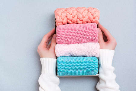 Organization and order. Women's hands hold a box of neatly folded knitted clothes. Top viewの写真素材