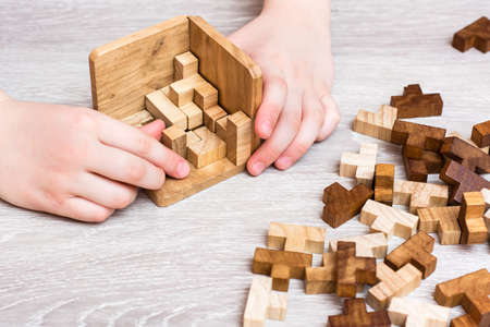 Organization and order. Children's hands fold the wooden puzzle pieces into a folding mold. Leisure for childrenの写真素材