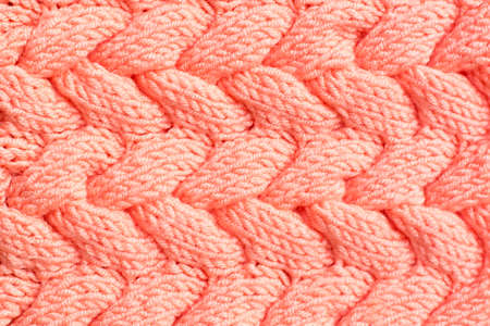 Textured background. Knitted fabric in peach color in the form of intertwined braids. Top viewの写真素材