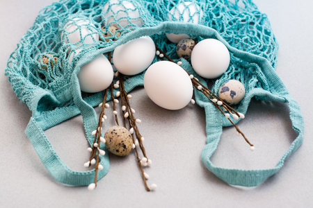 Happy Easter. Eggs and pussy willow branches in a string bag on a gray background.の写真素材