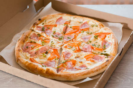 Takeaway food. Pizza in a cardboard box on the table in the kitchen. Close-upの写真素材