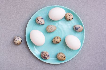 Happy Easter. Chicken and quail eggs on a plate on a gray background. Top viewの写真素材