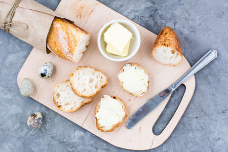 Tasty breakfast. Fresh baguette sandwiches with butter and quail eggs on a cutting board on the table. Top viewの写真素材