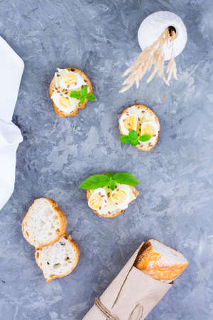 Hearty breakfast in the morning. Fresh baguette sandwiches with butter, quail eggs, flax seeds and basil seeds on the table. Vertical view. Top viewの写真素材