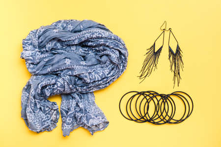 Beautifully curved cotton neck scarf, bracelets and earrings on a yellow background. Spring outfit, fashion accessoriesの写真素材