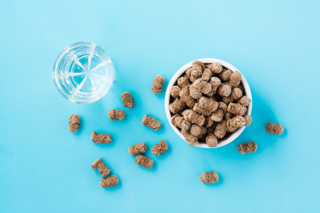 Rye bran in a bowl and on the table and a glass of water on a blue background. Diet and cleansing...
