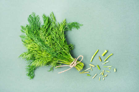 A bunch of fresh dill and cut ends of the stems on a green background. Vitamin greens in a healthy diet. Top viewの写真素材