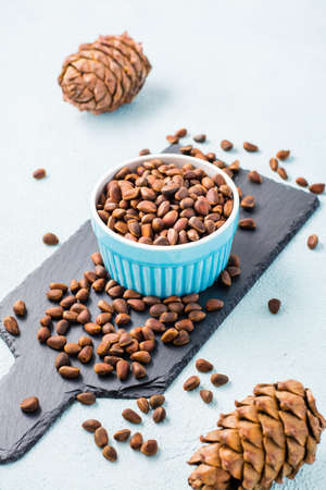A bowl of unpeeled pine nuts and pine cones on a slate board. Detox and cure for insomnia. Healthy...