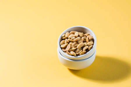 Salted peanuts in a white bowl on a delt background in hard light. Healthy modern vegetarian food.の写真素材