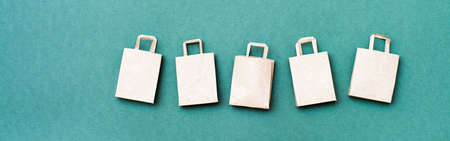 Eco-friendly craft paper shopping bags in a row on a green background. Black friday gift sales. Web bannerの写真素材