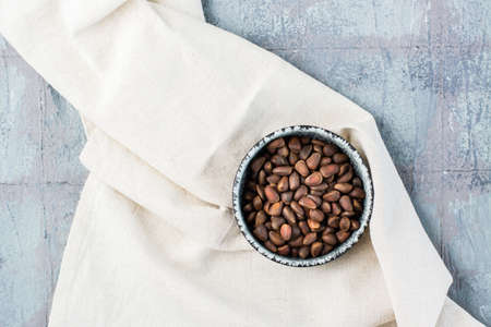 Pine nuts in a bowl on a cloth on the table. Vegetarian food. Wellness, detox and vitamin nutritionの写真素材