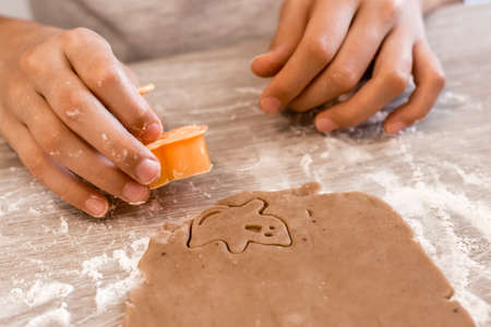Preparing to celebrate halloween and preparing a treat. Children cut out from rolled dough to bake cookies for Halloween at home in the kitchen. Lifestyleの写真素材
