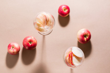 Refreshing cocktail of apple pieces and mineral water in glasses on a brown background in harsh light. Detox wellbeing drink. Top viewの写真素材
