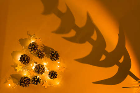 Christmas at sunset. Deer garland, pine cones and a tree shadow in warm orange light. Top view