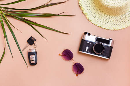 Summer bright travel flat lay with sunglasses, car keys, vintage camera and straw hat on beige background. Car travel. Top viewの写真素材