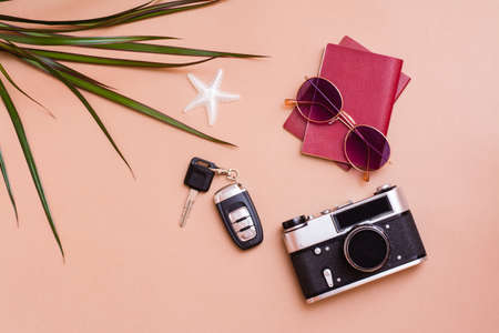 Bright travel flat lay with sunglasses, passports, vintage camera and car keys on a beige background. Car travel. Top viewの写真素材