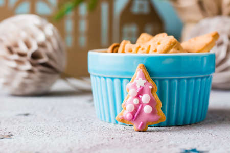 Christmas cookies spruce with pink icing are placed near a bowl of cookies on a decorated table. Festive treat. Close-upの写真素材