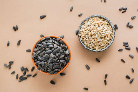 Choose between peeled and unpeeled sunflower seeds in bowls on the table. Natural source of vitamins and fat. Top viewの写真素材