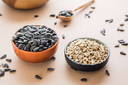 Choose between peeled and unpeeled sunflower seeds in bowls on the table. Natural source of vitamins and fatの写真素材